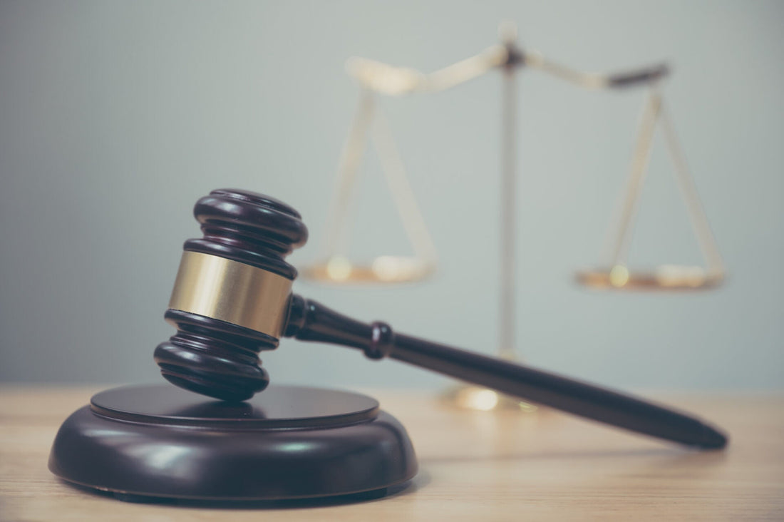 Wooden and gold gavel with gold scale in the background. 