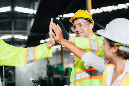 Three construction workers in a group giving high fives