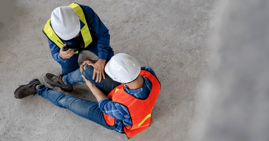 Construction Workers kneeling down looking at an injured personsleg