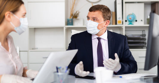 Workers at a desk with computers wearing masks