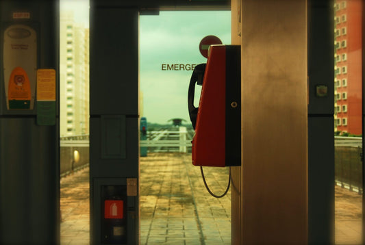 Phone on a wall with glass door in the background with Emergency on the door